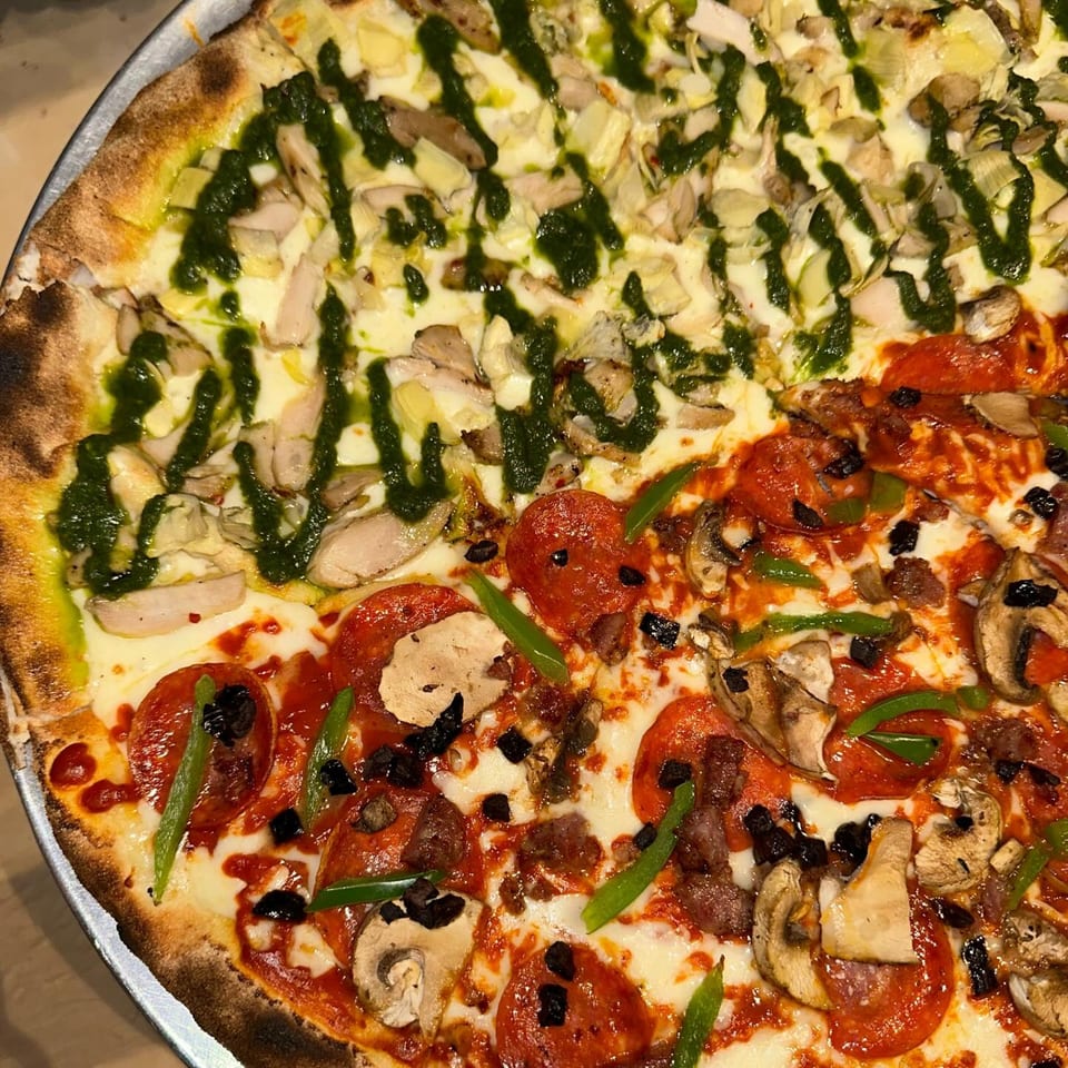 A half-and-half pizza with pesto chicken artichoke and pepperoni mushroom toppings from Pj's Pizza Co.