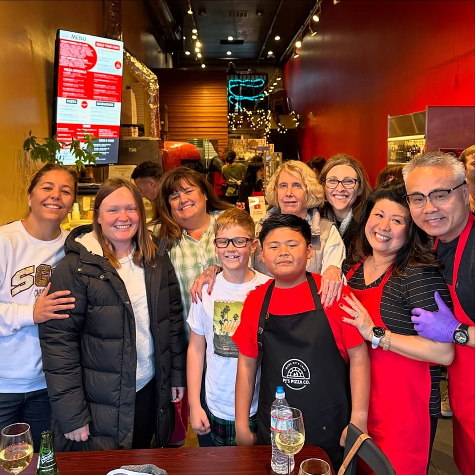 A group of smiling people, including children and adults, posing together inside Pj's Pizza Co.